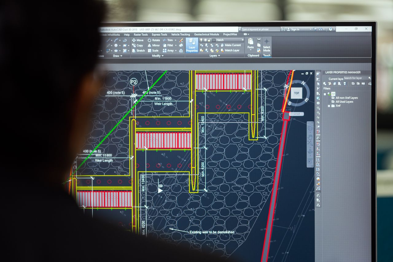 Crafting Captivating Headlines: Your awesome post title goes here A civil engineer working on a weir design using CAD software on a computer screen in an office setting.